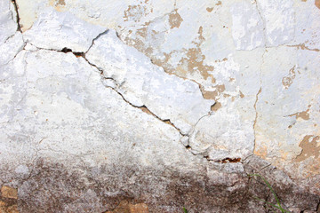 the background of the cracked white wall of the house is old covered with plaster and the paint is peeling from time. Very old house. cracks in the wall