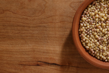 Fregola sarda dentro ciotola in ceramica, sopra tavolo di legno