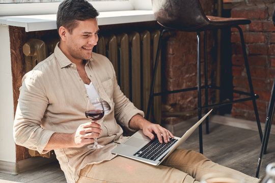 Man with a wineglass typing on his computer