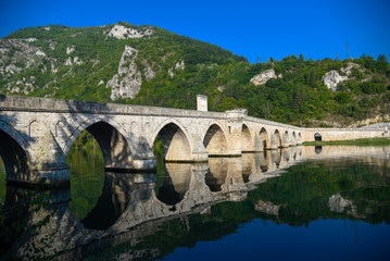 The Ottoman Mehmed Pasa Sokolovic Bridge in Visegrad, Bosnian mountains, with fantastic sky scape and river reflection. Bosnia and Herzegovina.