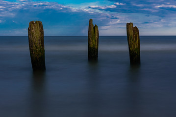 the old wooden piles of the boat berth on the sea shore