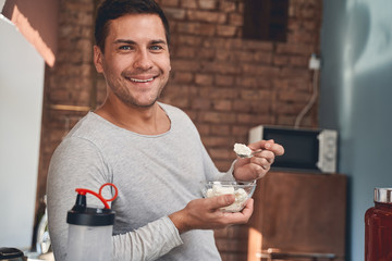 Merry pleased sportsman enjoying protein-rich cottage cheese