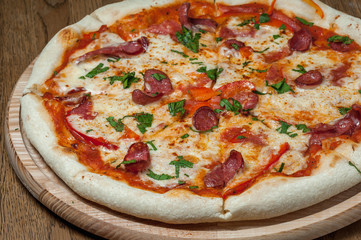 pizza on a wooden tray stands on a wooden table
