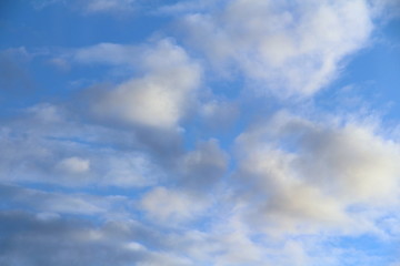 Fototapeta premium Chmury na niebieskim niebie o zachodzie słońca lub świcie podświetlone przez słońce. Miejsce na tekst i projekt.