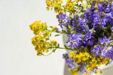 Spring flowers in a vase top view. Beautiful yellow and purple flowers in a glass vase. Flowers on a white background