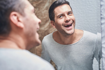 Fototapeta premium Man staring at his teeth in the mirror