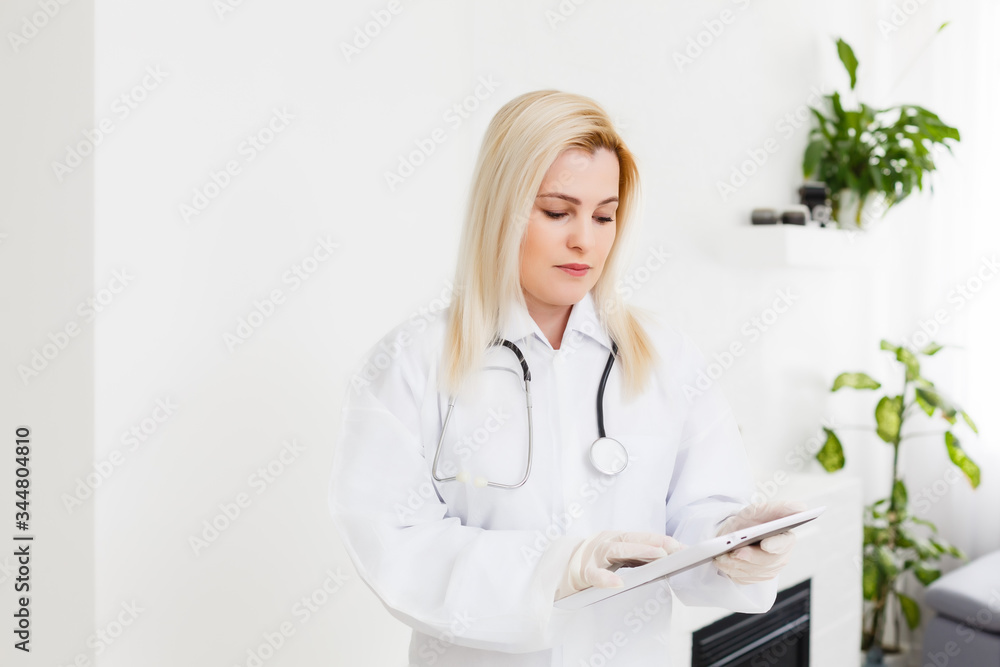 Wall mural female runette doctor using tablet, intelligent and lovely woman with the gadget and stethoscope in 