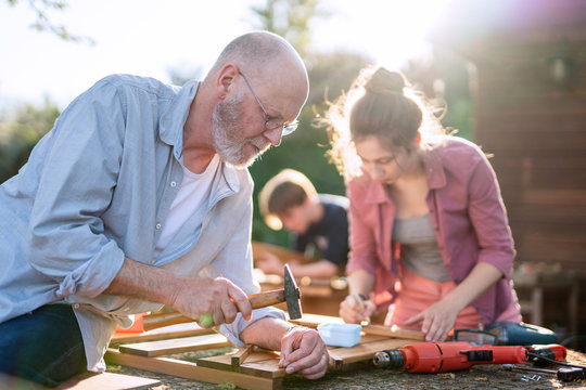 A Man And His Family Are Building Wooden Planters For Their Vegetable Garden