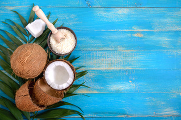 Whole coconut, shell, green palm leaves on a blue wooden background. Copy space. Top view, flat lay. Tropical background.