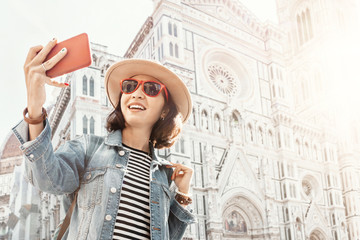 Happy girl travel blogger takes a selfie photo on a smartphone against the background of the main...