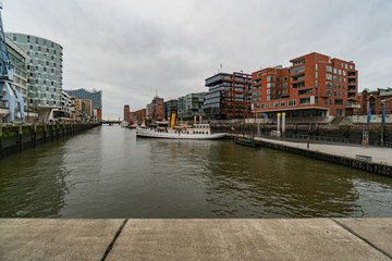 The Harbor District (HafenCity) in Hamburg, Germany. A view of the Sandtorkai with some old ships on a cloudy day with a dramatic sky.