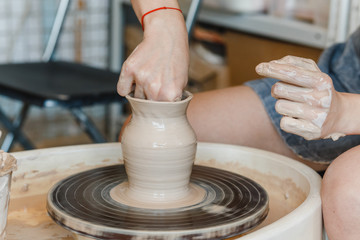 Close-up of female hands sculpting clay on a Potter's wheel. Concept of hobby and cretivity at home and in the Studio workshop