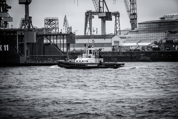 Hamburg container port with a tugboat in closeup view in front of it, Germany