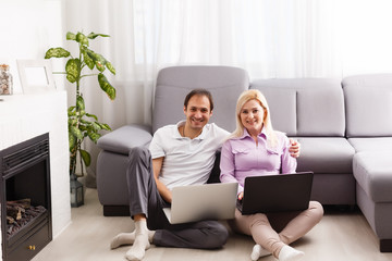 Happy young casual couple sitting working together at home office, smiling.