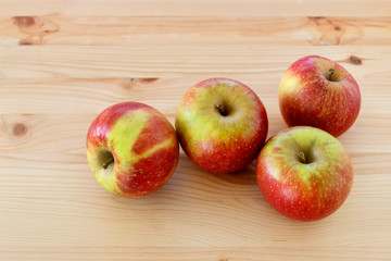 Red and yellow apples on wooden table.