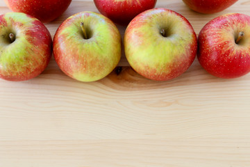 Red and yellow apples on wooden table.