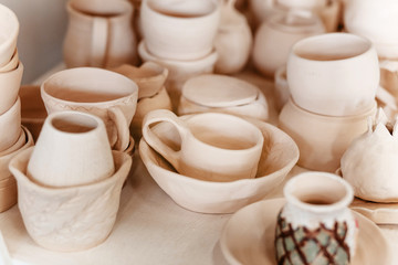 Fototapeta na wymiar Raw ceramic pottery kitchenware drying on the shelf. Art workshop concept