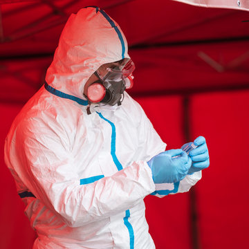 Medical staff with face mask and professional uniform sticks sample designation of test swob of Sars-Cov-2 .