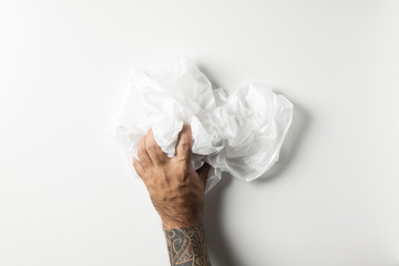 Man hand with tattoos squeezing a crumpled foam sheet isolated on white background.