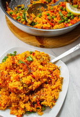 Vegetarian paella on a white plat with a fork. Spanish yellow paella with a slice of lemon as garnish. 