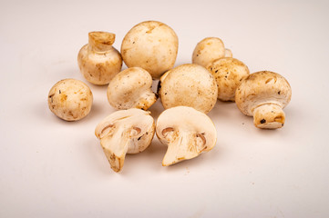 Halves of cut young mushrooms and young mushrooms scattered on a white background. Close up.