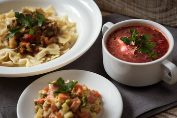 Complex dinner on the table. Pasta, soup, salad.