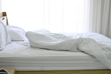 Messy white bedding sheet and white pillow after waking up in the morning with sunshine shining...