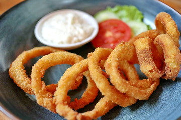 Unfocused, Blurry selective focus image fried onions with flour or onion ring, served with mayonase sauce, cucumber and tomatoes.  