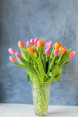 Bouquet of tulips in vase. Spring flowers . Bouquet in vase. Pink and orange blooming flora. Cozy still life. Copy space. Holiday greeting.
