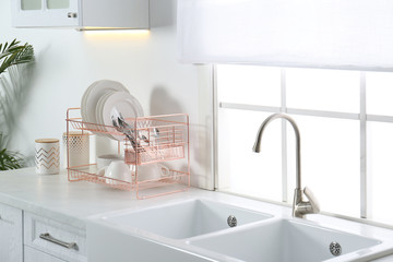 Clean dishes on drying rack in modern kitchen interior