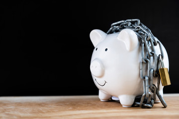 White Piggy bank locked, chained with black background, Protect savings, Protect capital, Protect retirement fund concept