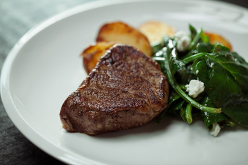 Beef steak with spinach and potatoes on white plate