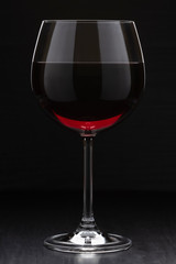 a glass of wine standing on the surface. vertical image on a dark background.