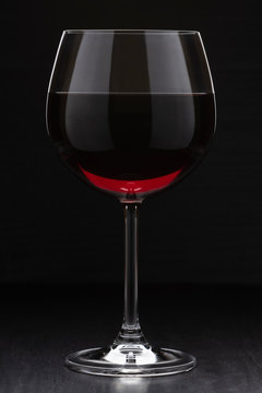 a glass of wine standing on the surface. vertical image on a dark background.