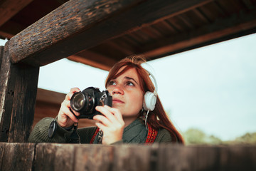 Young woman taking photos from wooden hut in the forest