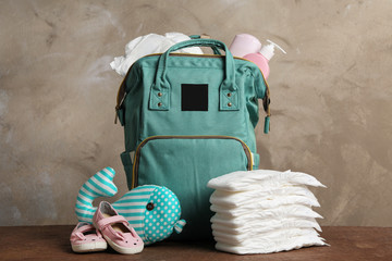 Bag with diapers and baby accessories on wooden table