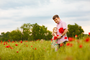 child with dad picking flowers in poppy field