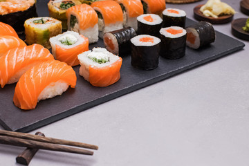 Set of sushi and maki rolls with wasab on black stone tray
