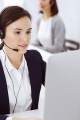 Call center. Beautiful woman sitting and working in headset at customer service office. Business concept