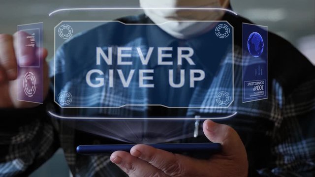 Unrecognizable elderly man in a protective mask interacts with HUD holograms on a smartphone with text Never give up. Old man in a plaid shirt with a holographic screen on a blurred background