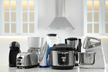 Set of modern home appliances on white marble table in kitchen