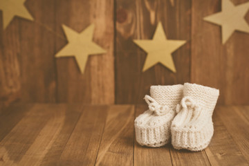 So cute! Handmade baby booties on wooden background in retro syle. Space for text