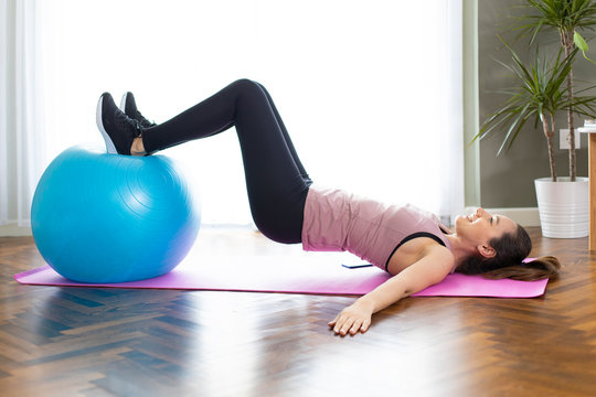 Young sporty woman using an exercise ball in her house.
