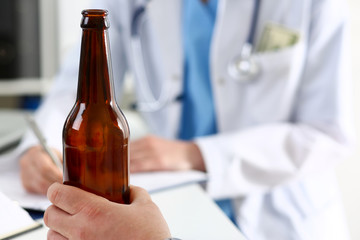 Alcoholic hold in hand empty bottle at doctor reception office closeup. Grief and despair,...