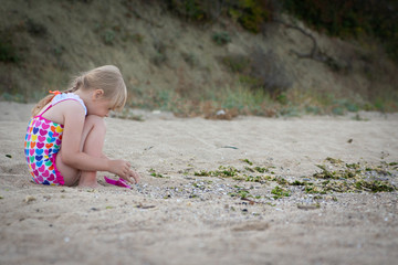 C hild playing with sand at the beach in summer.