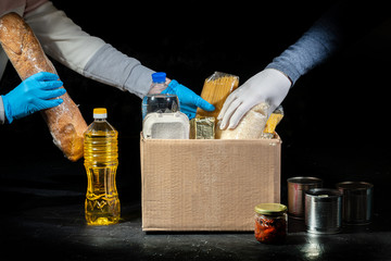 Volunteers putting different products in donation boxes on dark background