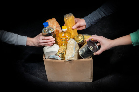 Volunteers putting different products in donation boxes on dark background