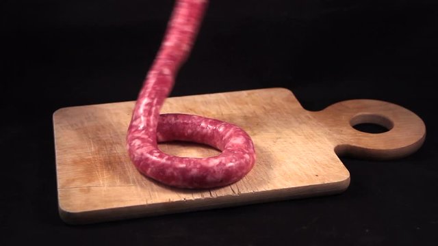 delicious fresh Italian pink pork sausage laid on a wooden cutting board on black  background