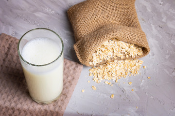 Oat milk in a glass on the table with dried fruit