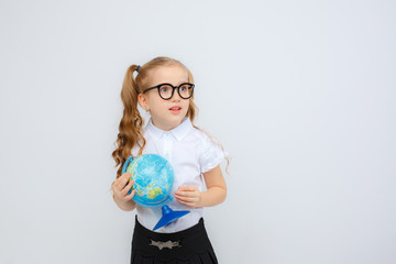 a little girl in school uniform and glasses holds a globe in her hands on a white background